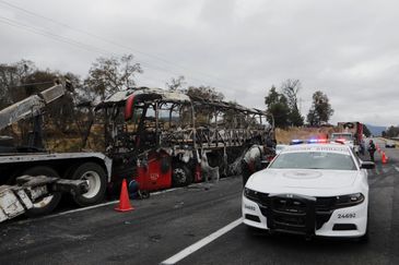 A burnt bus stands as members of the National Guard stand at the site on the highway connecting Mexico City with the state of Puebla, following roadblocks and arson attacks carried out by members of organized crime in several states after a military operation in which a government source said Mexican drug lord Nemesio Oseguera, known as 
